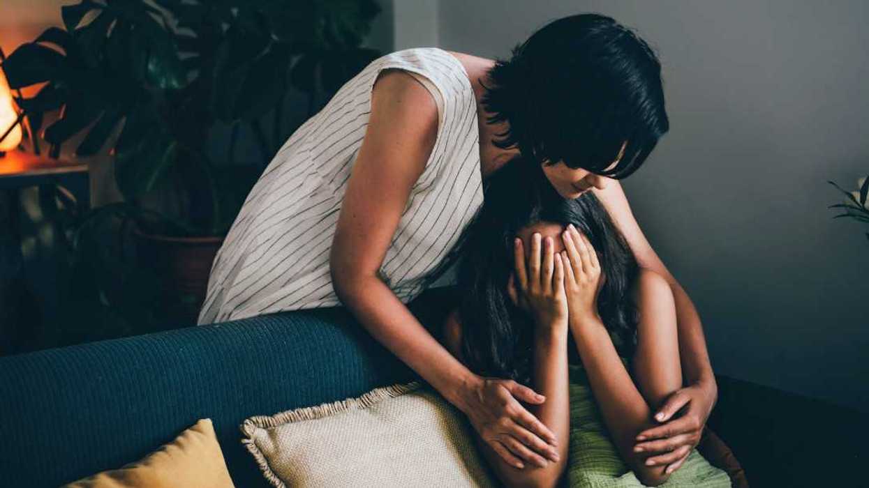 woman comforts teen girl on couch