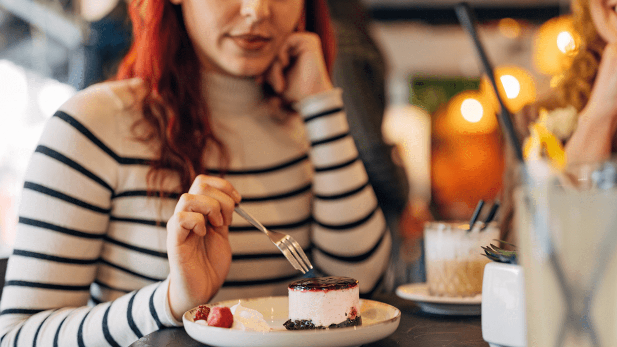 woman eating cheesecake in restaurant
