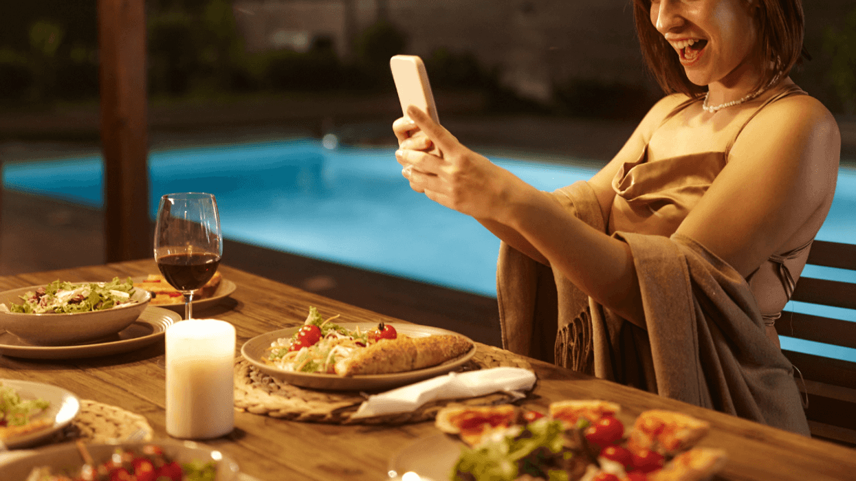 woman filming with phone at dinner