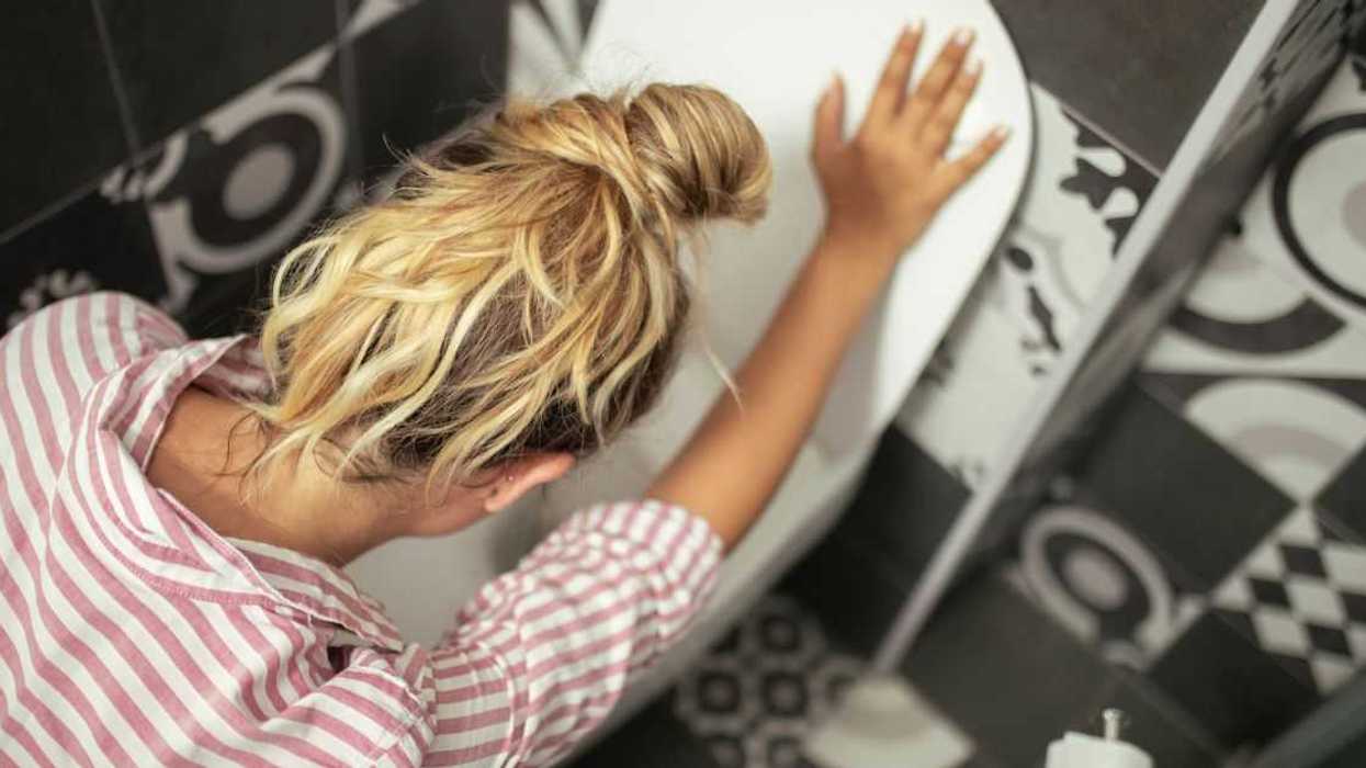 Woman getting sick and leaning over toilet