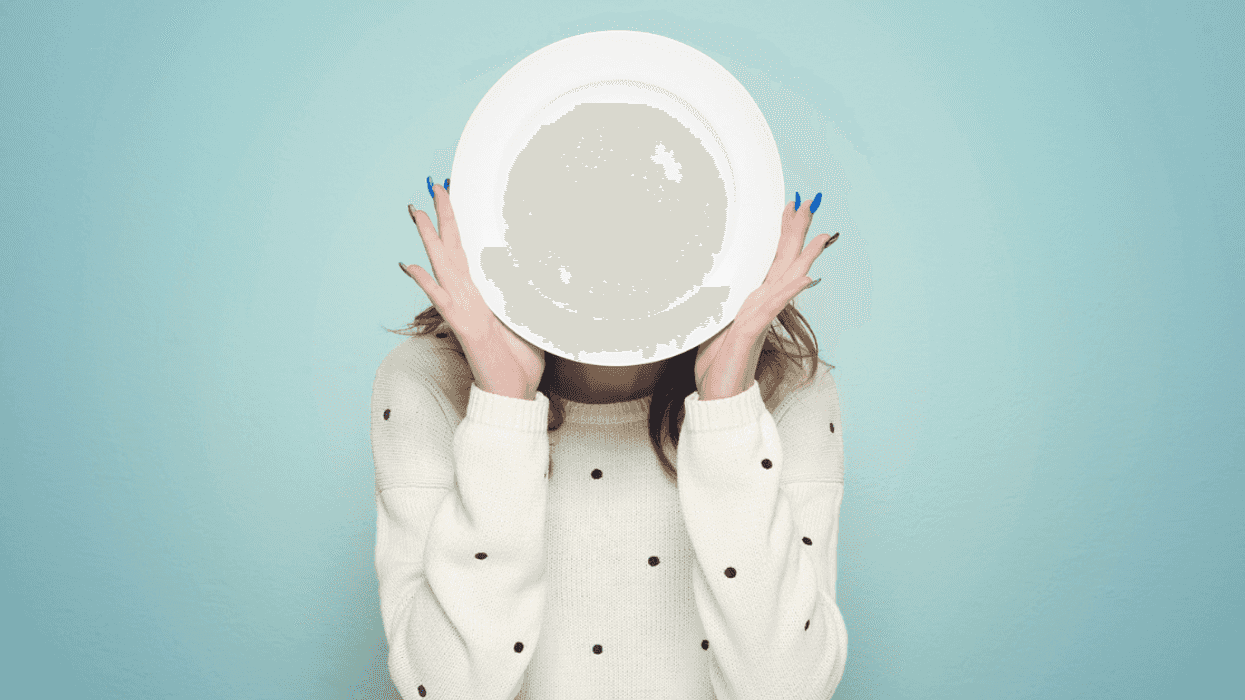 Woman hiding her face behind a plate.