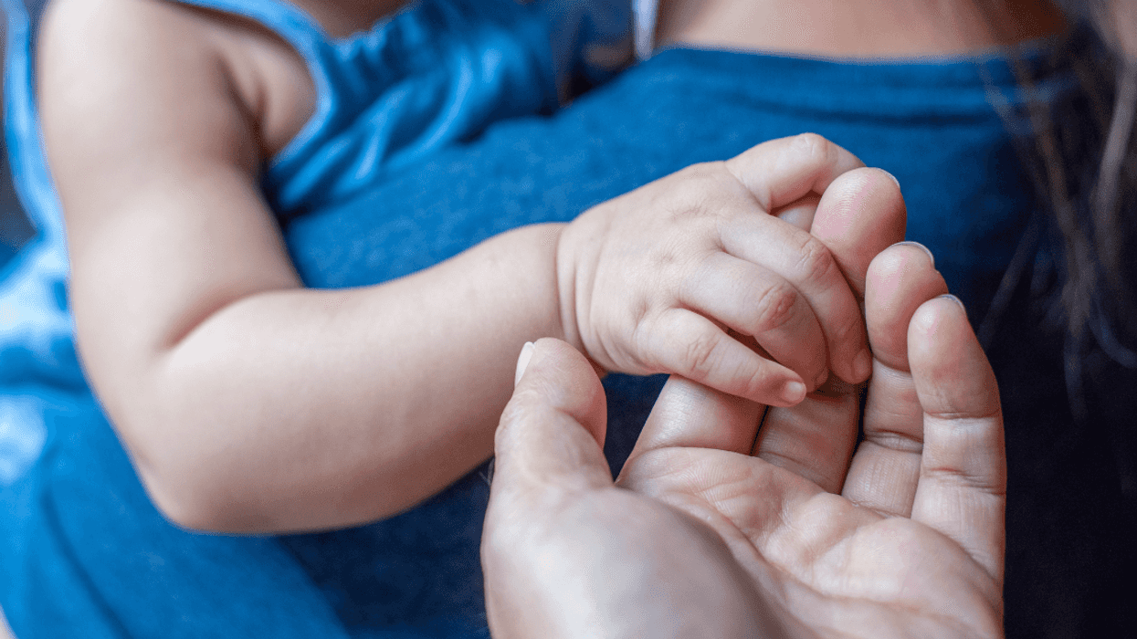 Woman holding baby, father holding baby's hand