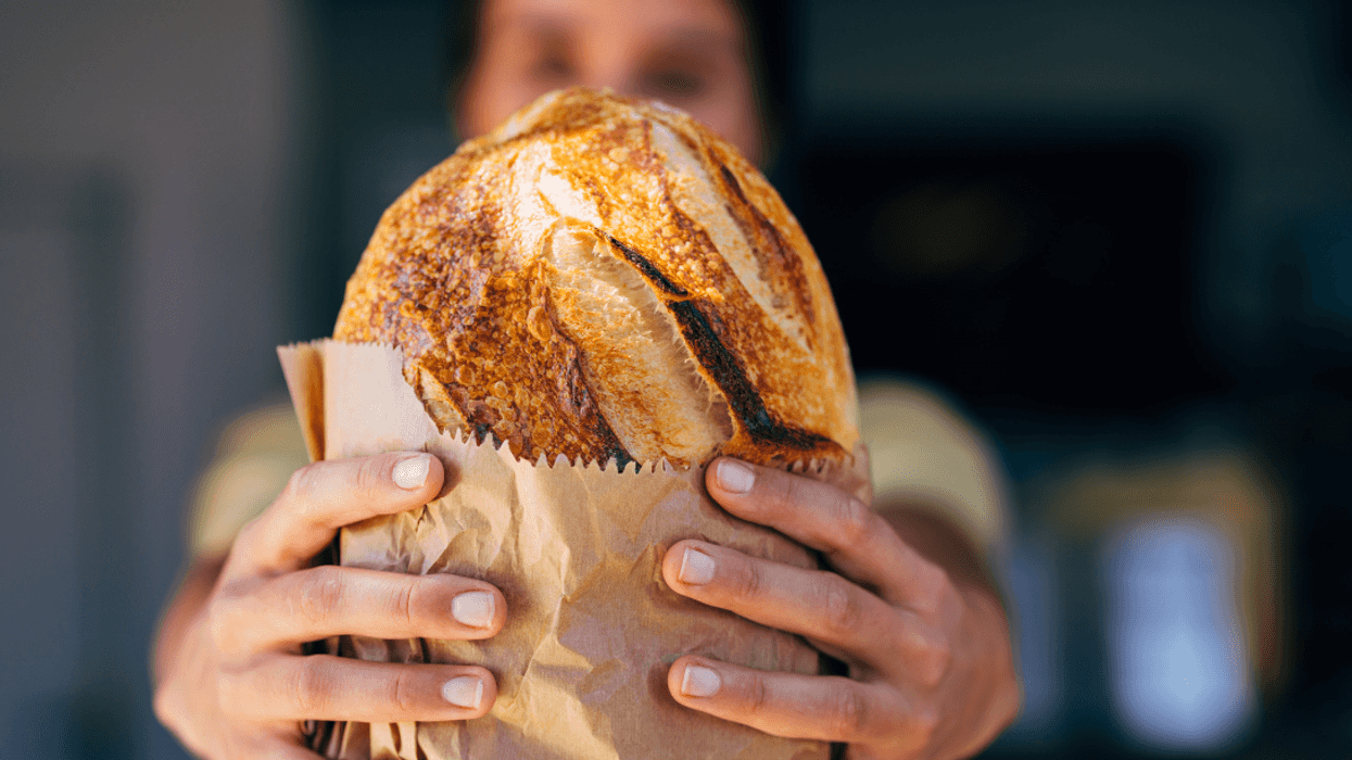 woman holding bread wrapped in brown paper
