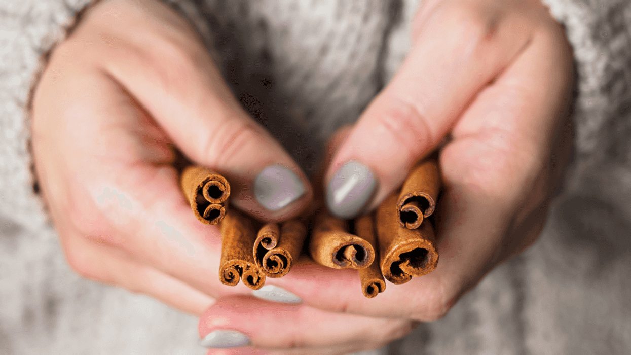 Woman holding cinnamon sticks.
