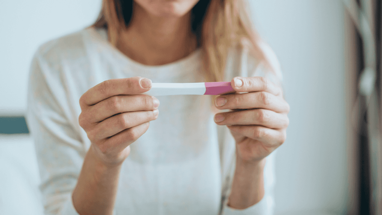 Woman holding pregnancy test.