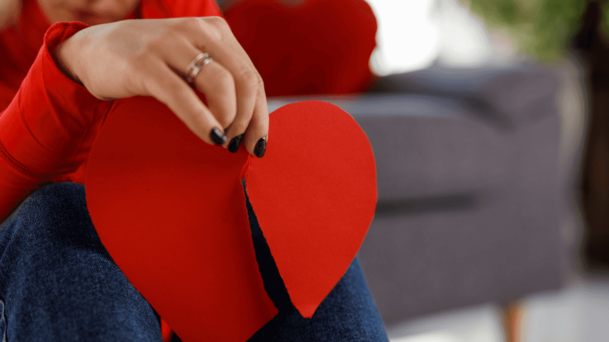 Woman holding up a paper heart that's been ripped in half