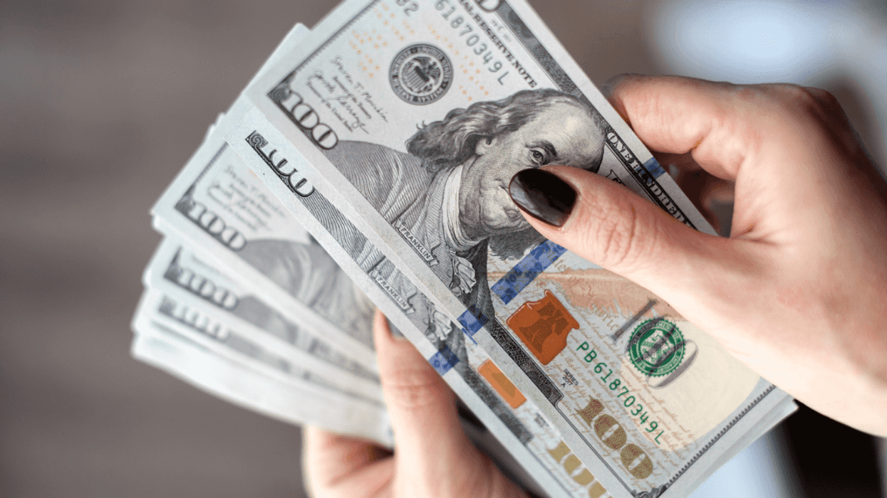 woman holds stack of $100 bills
