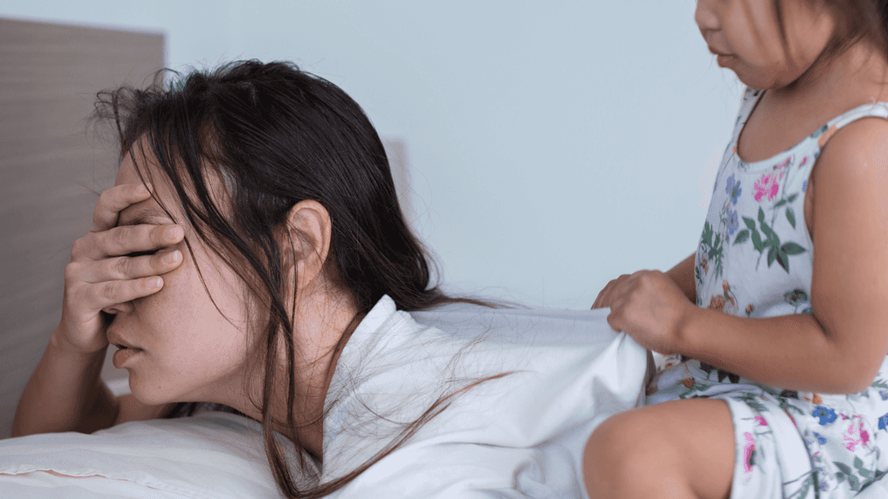 woman in bed ignoring child on her back