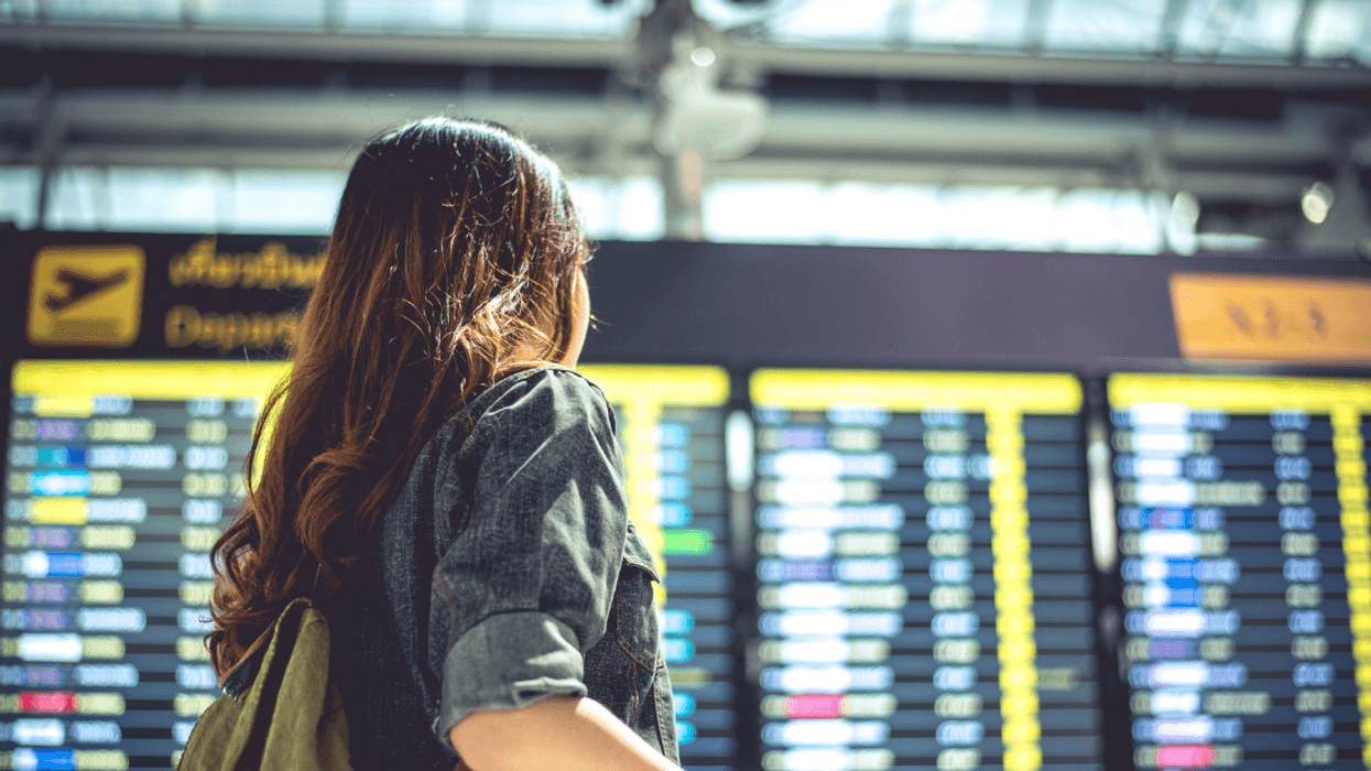 woman in front of airport arrival and departure board