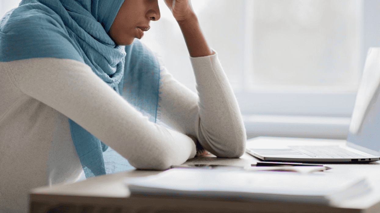 woman in hijab looking at laptop with concern