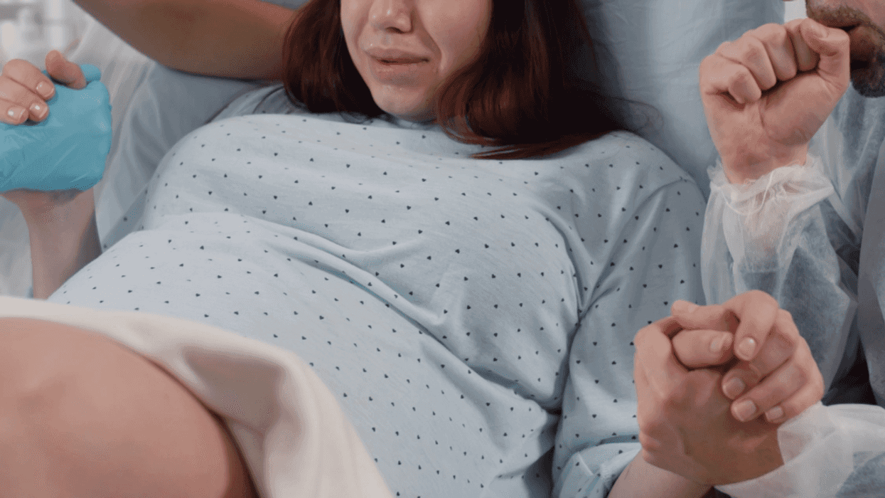 woman in labor flanked by a nurse and her male partner