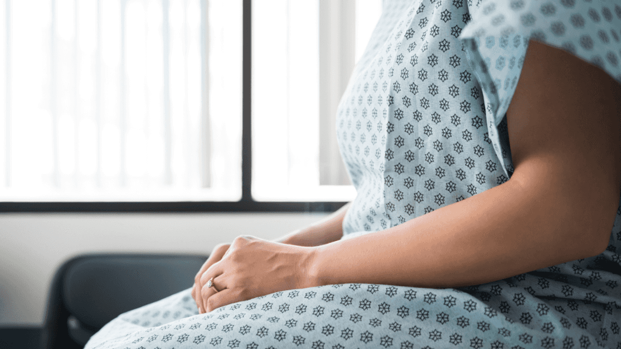 woman in medical patient gown seated on exam table