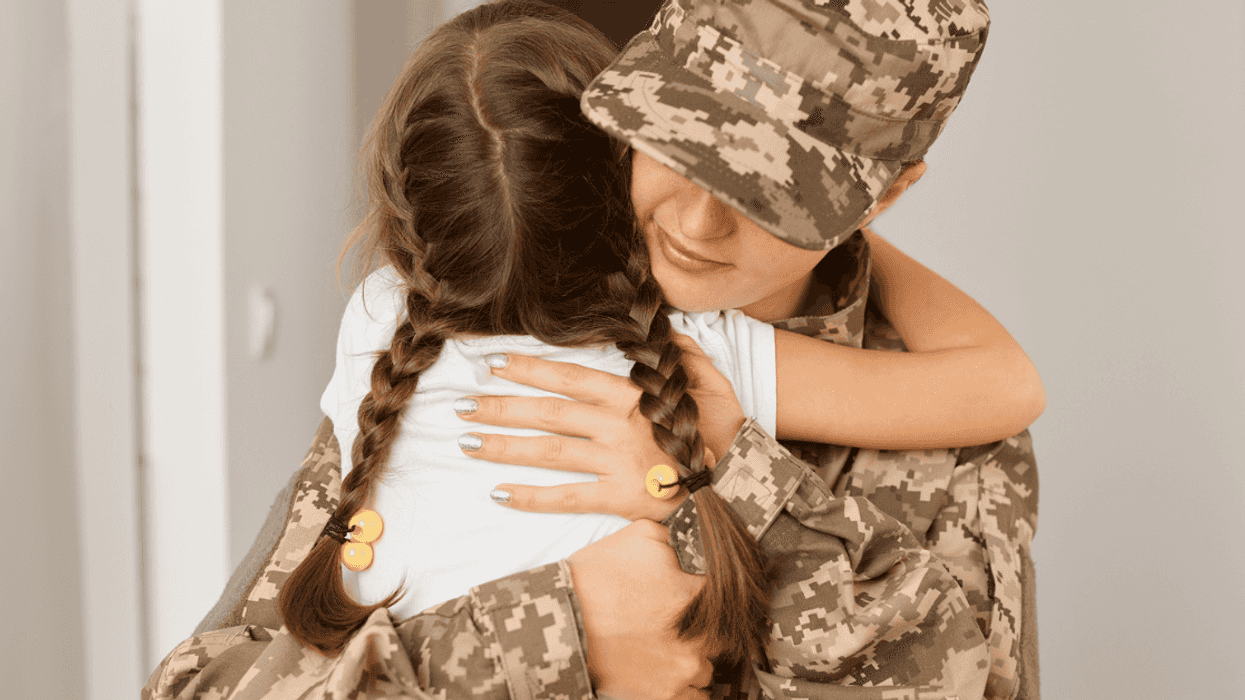 woman in military uniform hugging child