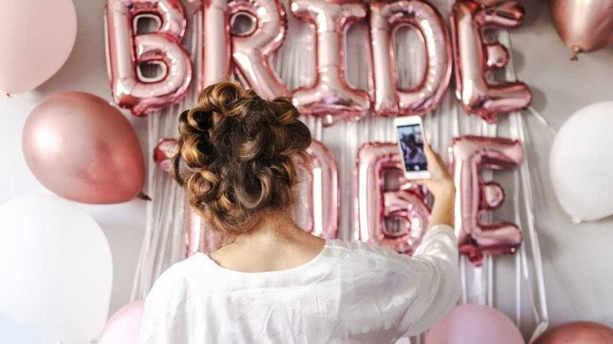 woman in white takes selfie in front of bridal shower decorations