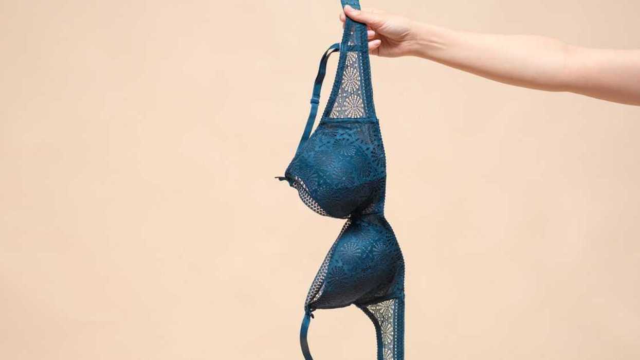 Woman is showing off a new blue bra in the hand. Choosing a new bra concept.