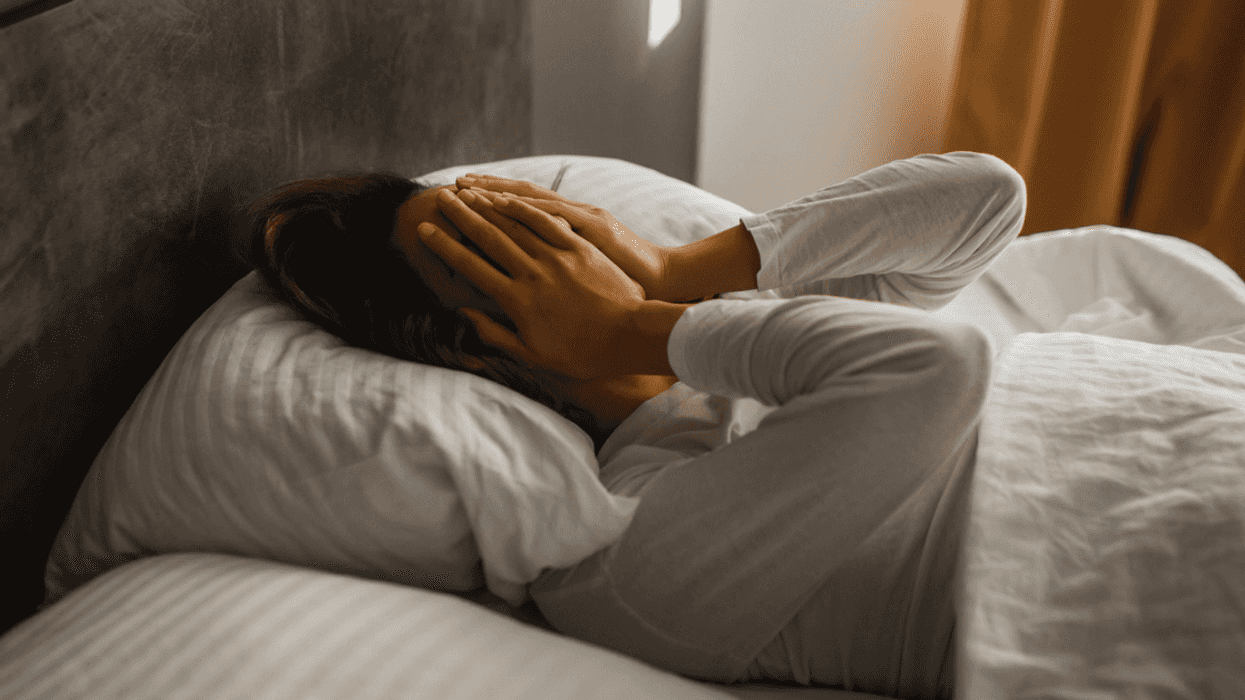 woman laying in bed with hands covering face