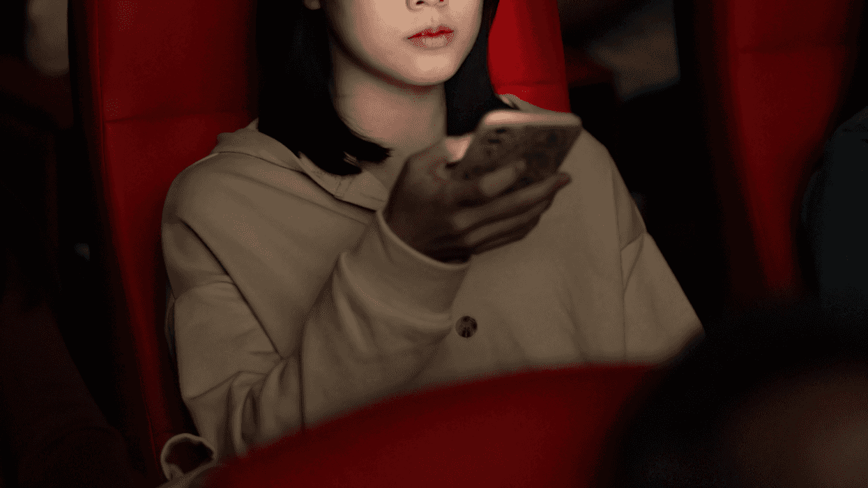 Woman on a phone in a movie theatre.