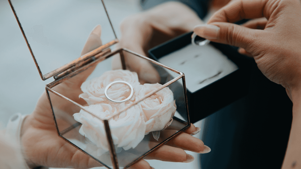 woman placing wedding rings on roses in glass box