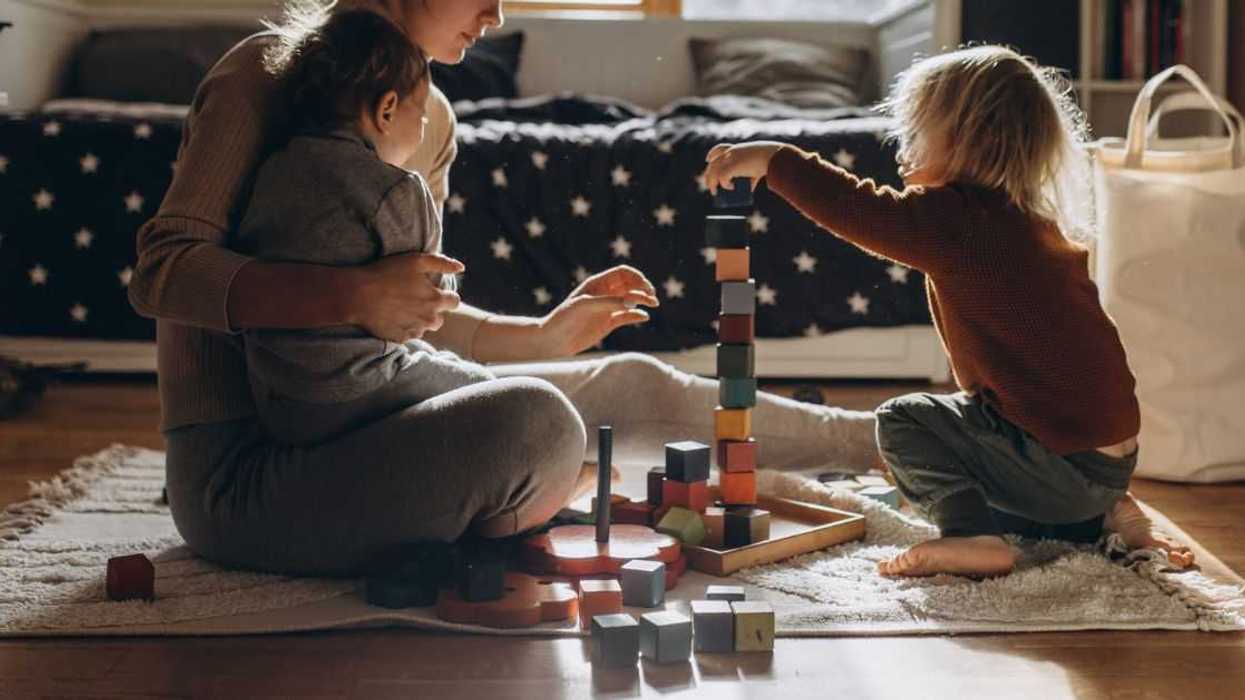 Woman playing toy blocks with two children