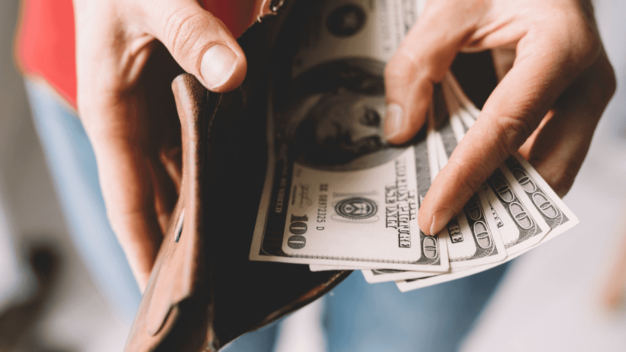Woman pulling hundred dollar bills out of wallet.