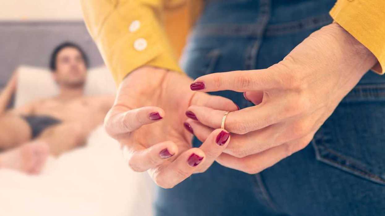 Woman removing wedding ring behind her back before laying with another man