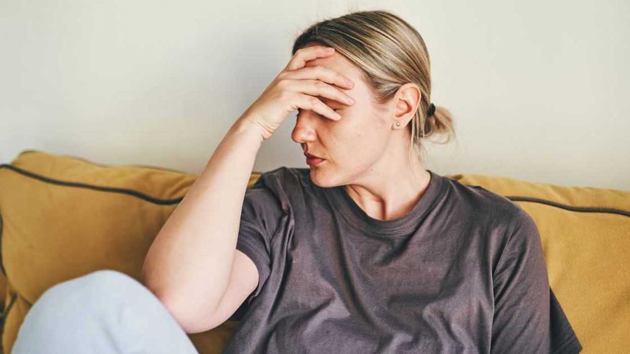 Woman resting forehead on her hand in frustration