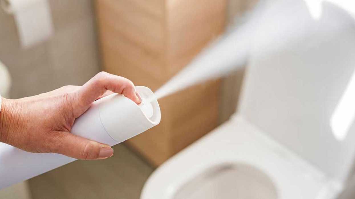 Woman's hand spraying air freshener to remove unpleasant odors of the bathroom.