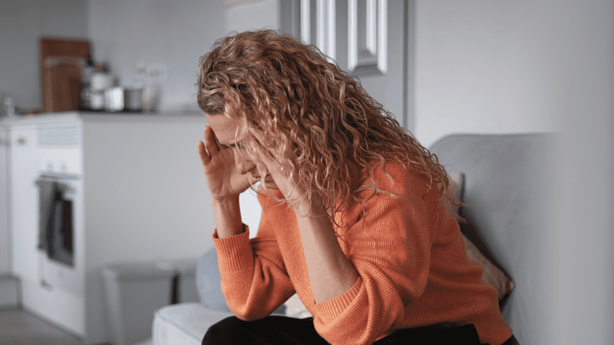 woman seated on couch with head in her hands