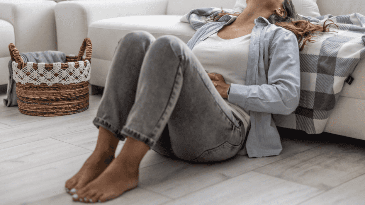 woman seated on floor holding stomach