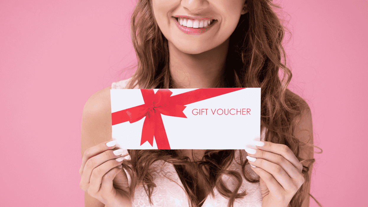 Woman smiling holding a gift card with pink background