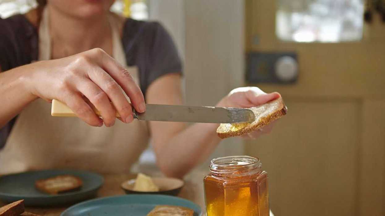 Woman spreading freshly extracted honey on bread.