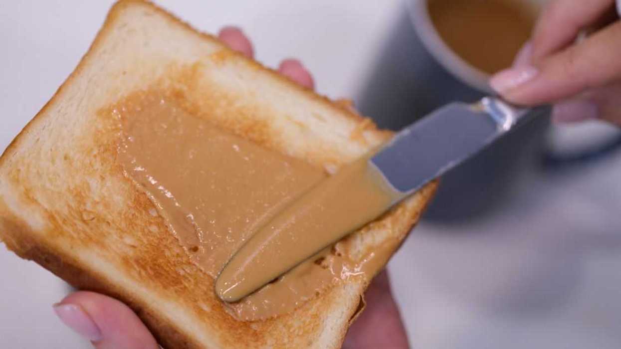 Woman spreading peanut butter on toast closeup. Quick breakfast concept