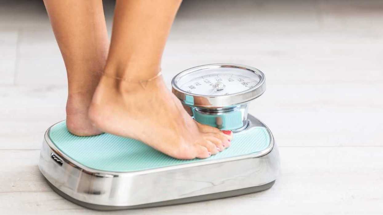 Woman standing on scale, close-up of legs and feet.