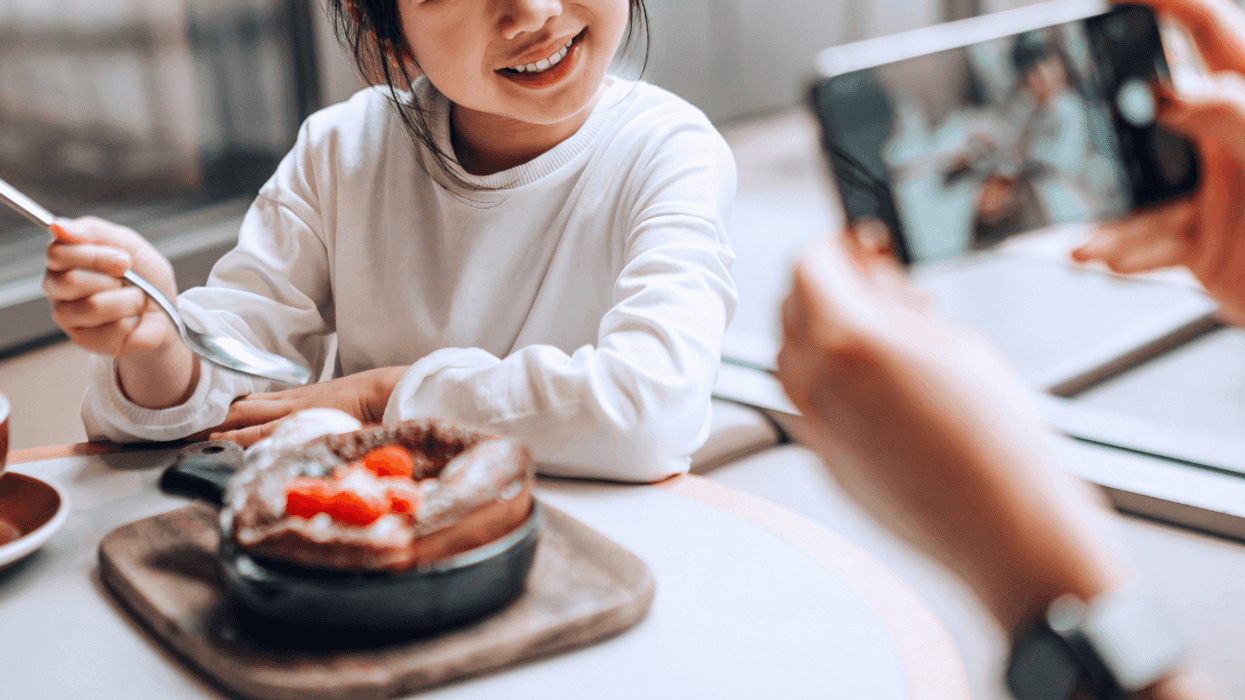 woman taking photo of child eating