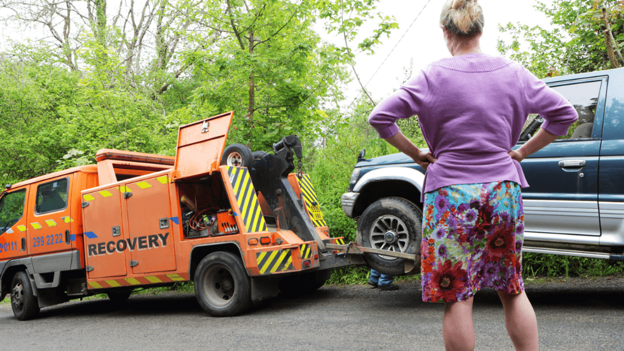 Woman watching car being towed.