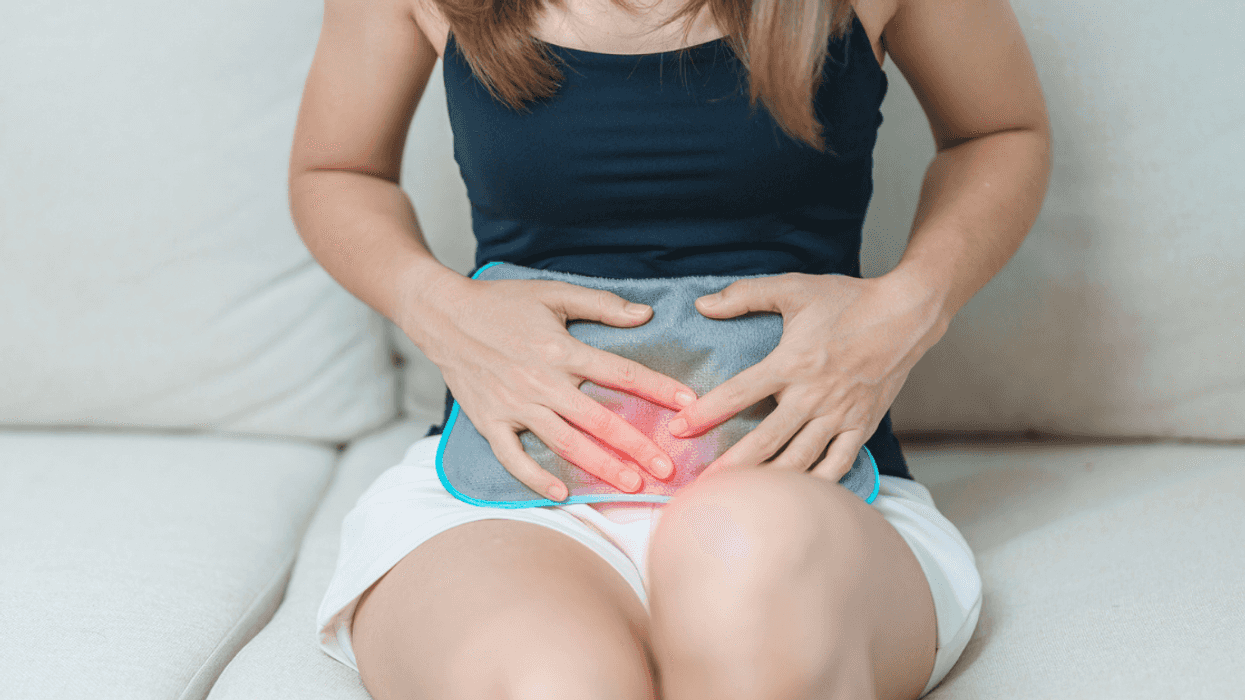 Woman with heating pad pressed to her stomach