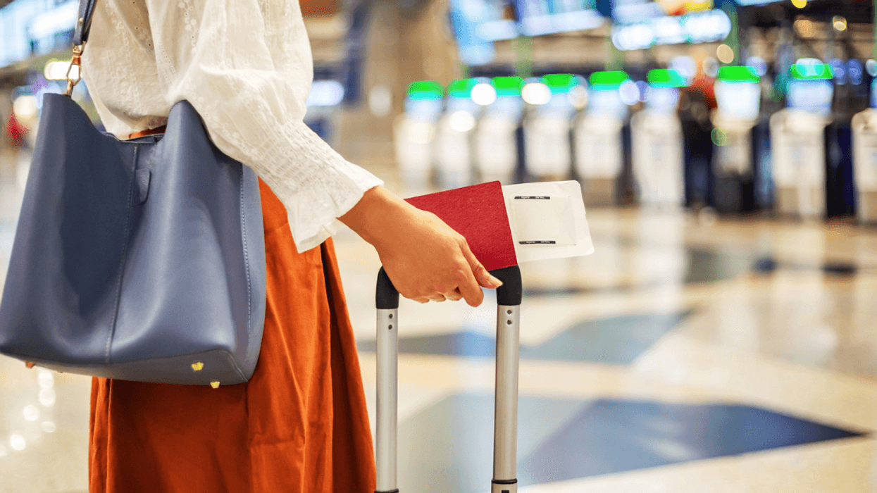 Woman with suitcase and passport in an airport.