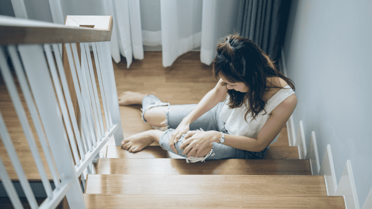 women in pain on stairs holding her knee