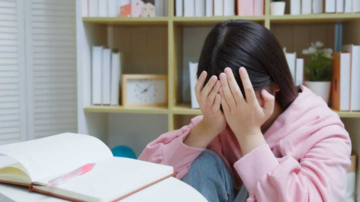 Young, crying girl studying at home.