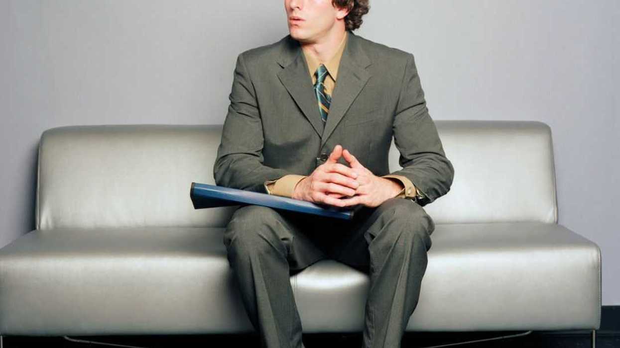 Young man sitting on sofa, looking off to side.