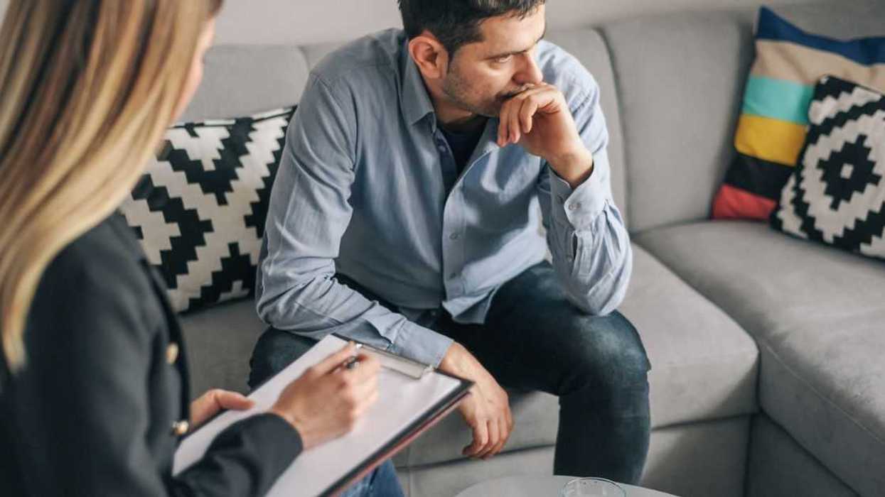 Young man, talking to female therapist about his problems, in therapy session