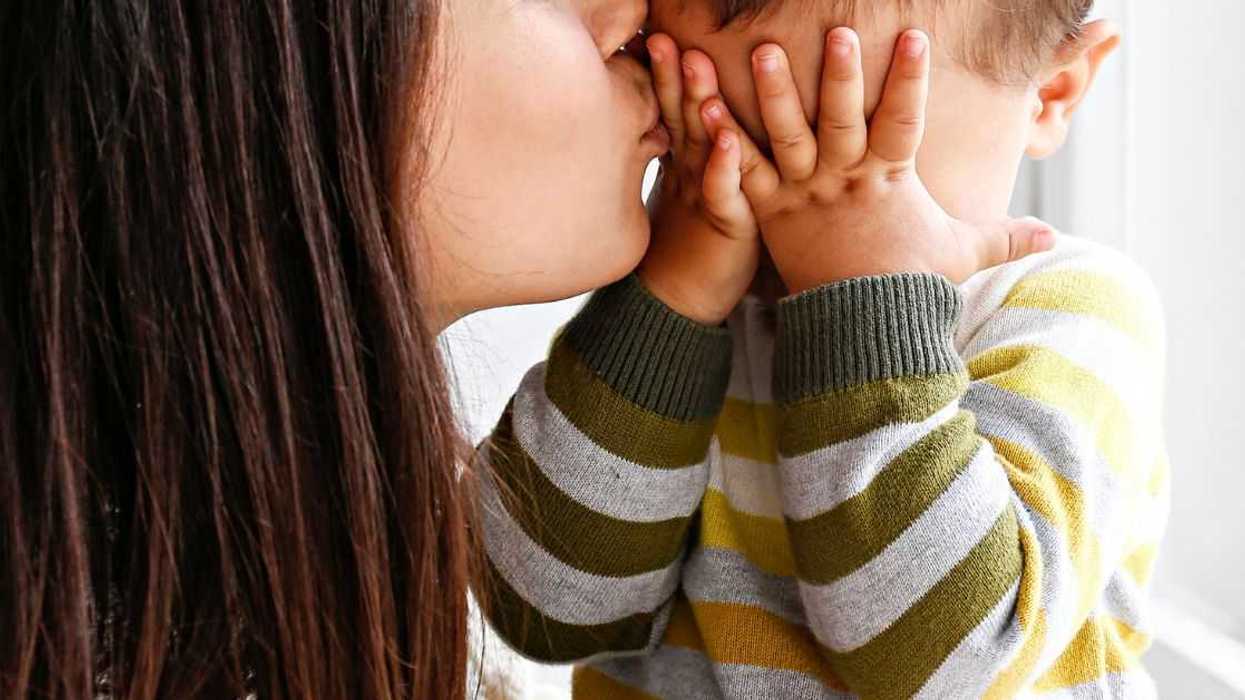 Young mother kissing baby son's forehead