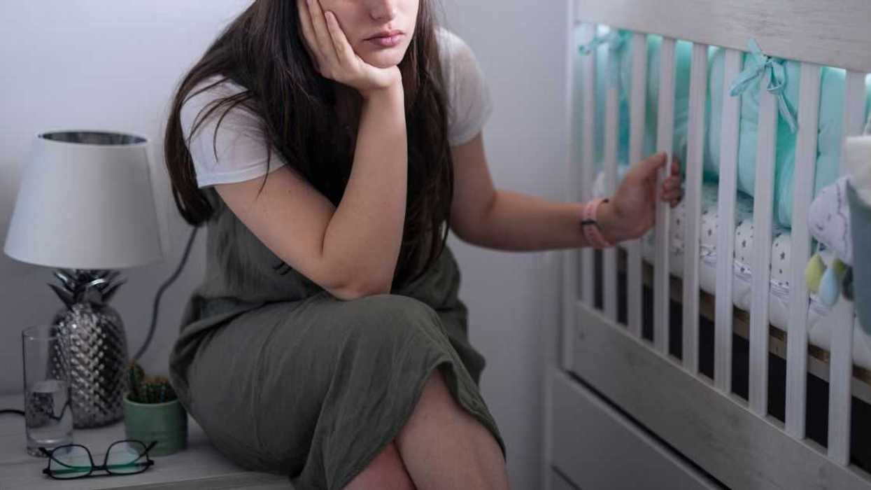 Young mother trying to put baby to sleep and suffering from insomnia.