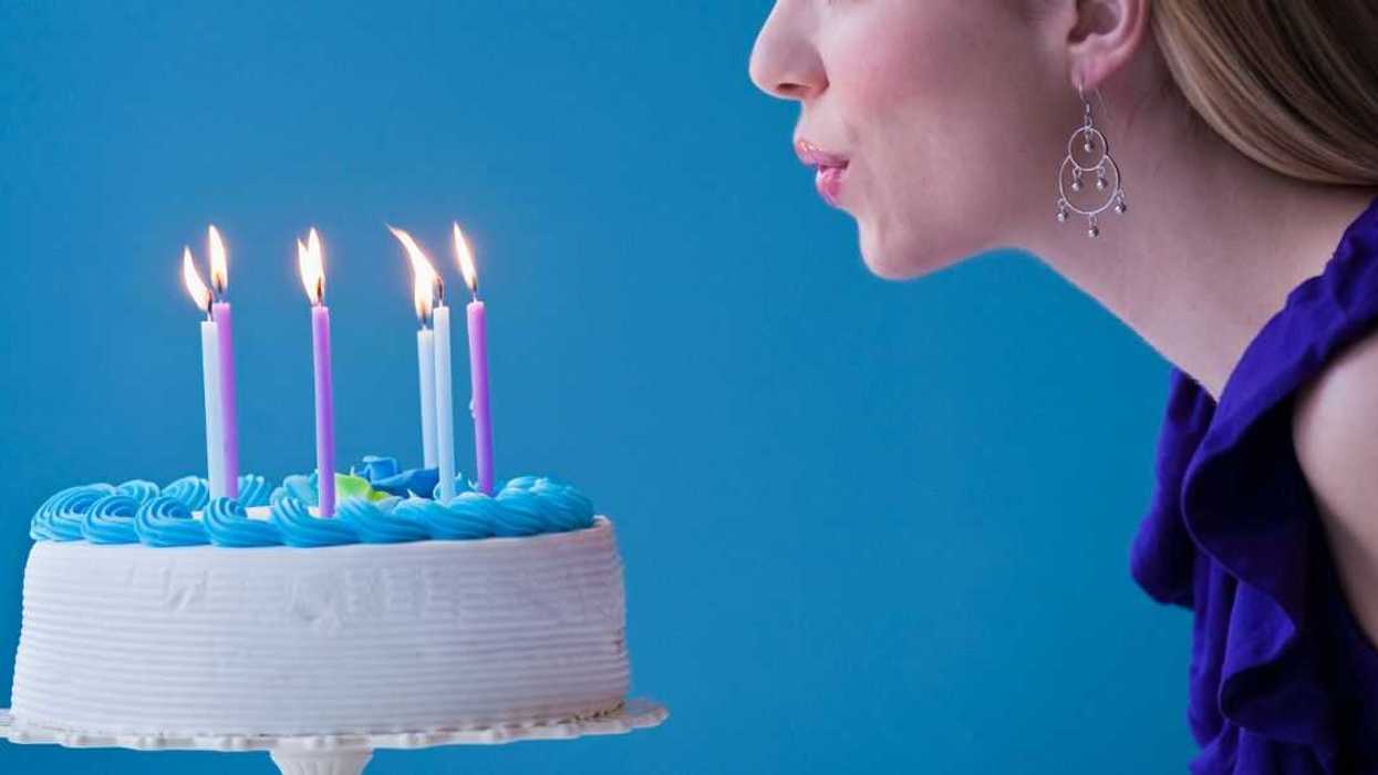 Young woman blowing candles on birthday cake.