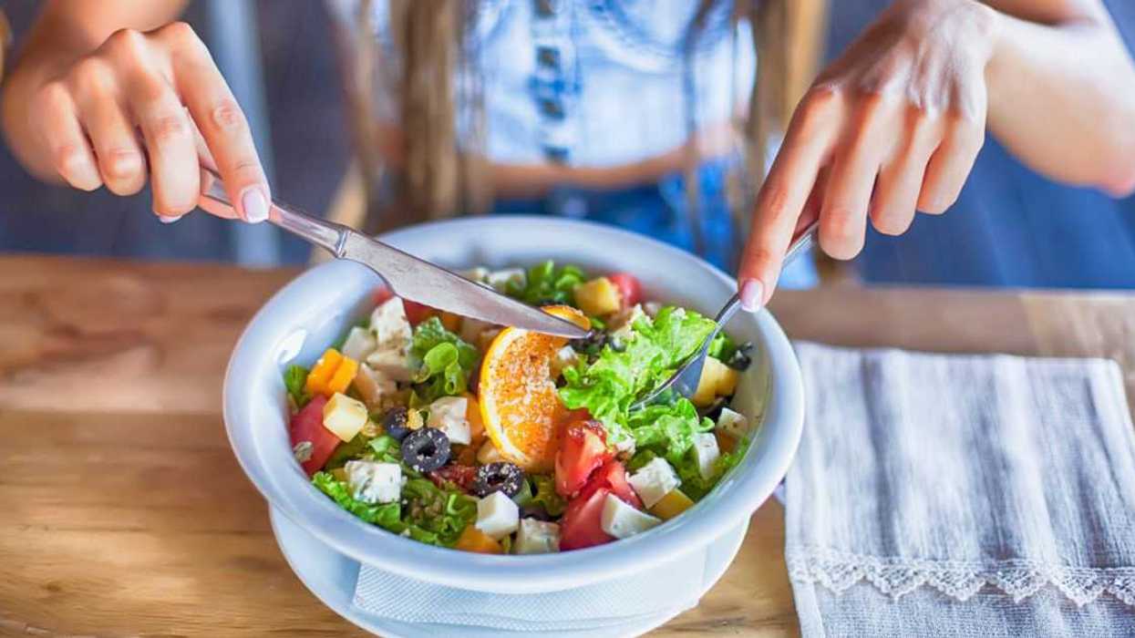 Young woman eating salad in restaurant, alone.