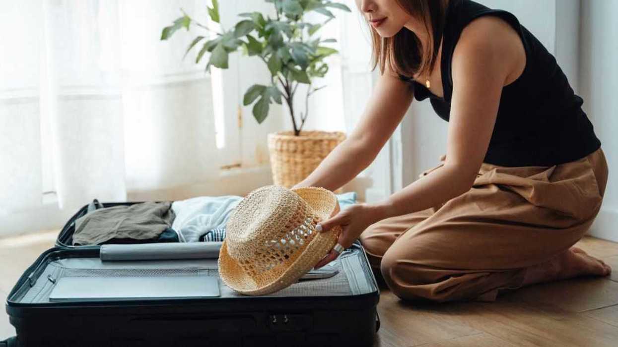 Young woman organising clothes in the suitcase, getting ready for vacation and business trip.