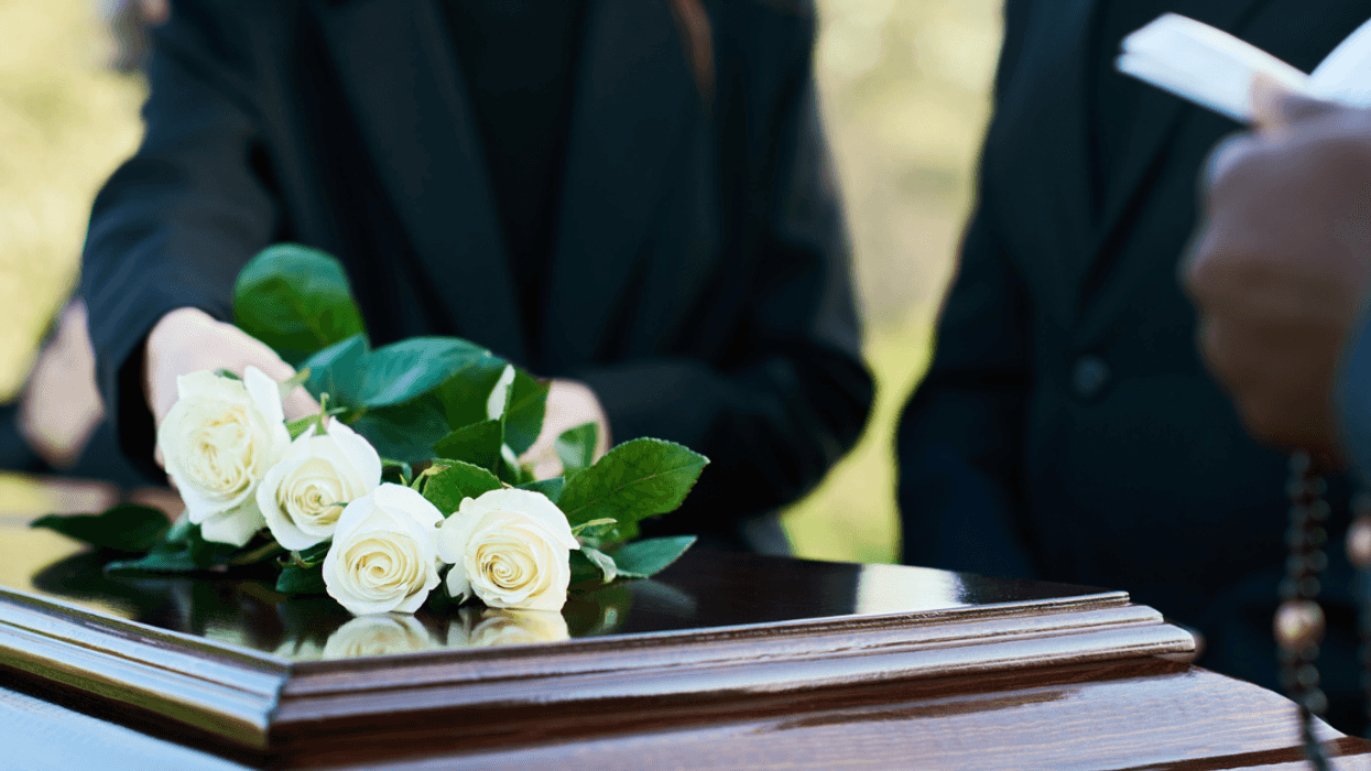 young woman places roses on a casket at funeral