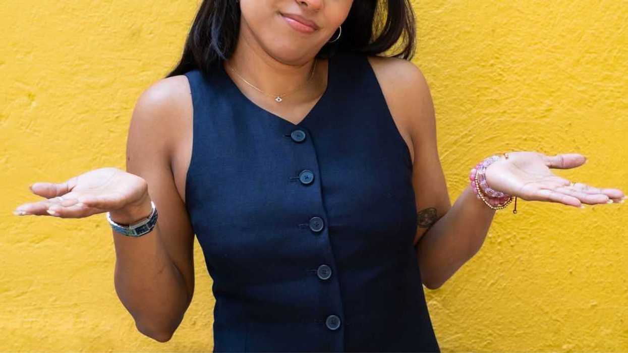 Young woman shrugging with her hands to the sides.