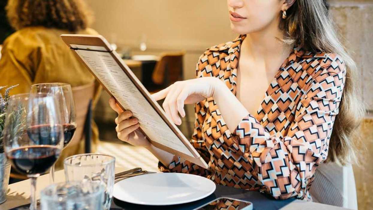 Young woman sitting in a restaurant and reading the menu.