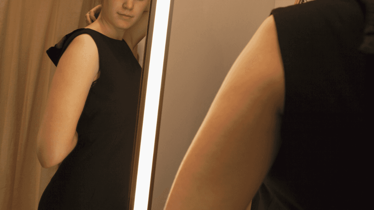 young woman trying on dress in front of mirror